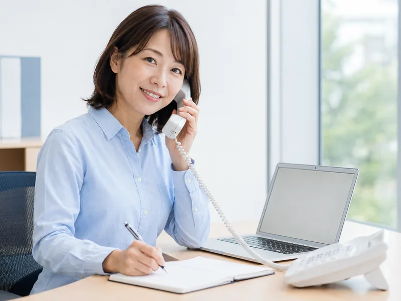 電話を受けながらメモを取る事務所の担当者